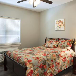 A cozy bedroom with floral bedding and a ceiling fan.