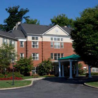 A residential brick building with a driveway and landscaped surroundings.