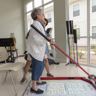 An elderly woman participates in a game of shuffleboard at a community center.
