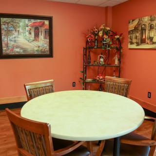 A cozy dining room with a round table and decorative artwork.