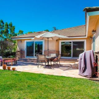 A cozy backyard patio with outdoor furniture and a large green lawn on a sunny day.
