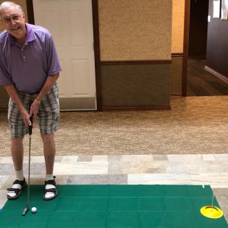 A man practicing indoor golf putting on a carpet.