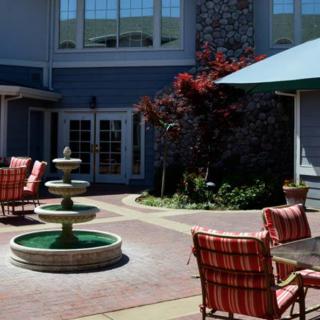 A peaceful courtyard with a central fountain and outdoor seating surrounded by a building.