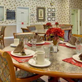 An elegantly set dining table with floral arrangements in a tastefully decorated room featuring floral wallpaper.