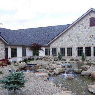 A stone building with a beautifully landscaped garden featuring a pond and rocks.