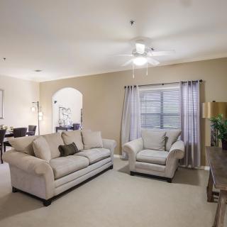 A cozy living room featuring a sofa, armchair, and soft lighting with a ceiling fan.