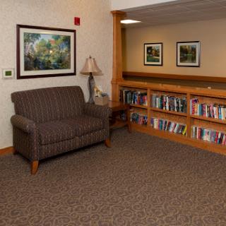 A cozy reading nook featuring a comfortable chair, a lamp, and a bookshelf filled with books.