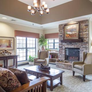 A cozy living room featuring a stone fireplace, comfortable seating, and ample natural light.