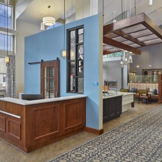 A modern reception area with a wooden counter and blue accent wall, featuring contemporary lighting and carpeted flooring.