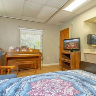 A cozy room with a piano, television, and a bed.