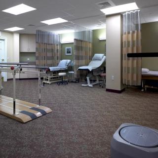 A clinical treatment room with chairs, privacy curtains, and medical equipment.