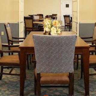 A cozy dining area featuring a wooden table and comfortable chairs, adorned with floral decorations.