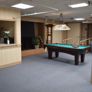 A spacious game room featuring a pool table and comfortable surroundings.
