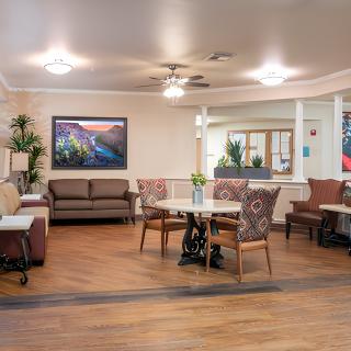 A cozy and well-lit seating area with tables, chairs, and a sofa in an interior space.