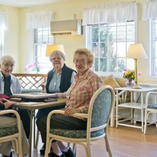 Three elderly women sitting together in a bright living room.