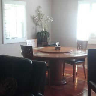 A cozy dining room featuring a round wooden table with four chairs and decorative elements by the windows.