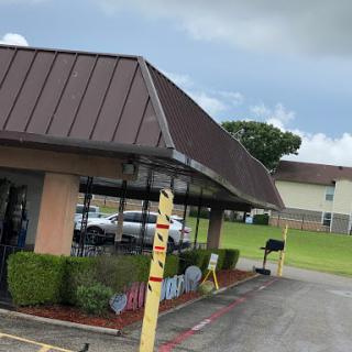 A view of a fast food restaurant with a drive-thru area under a cloudy sky.