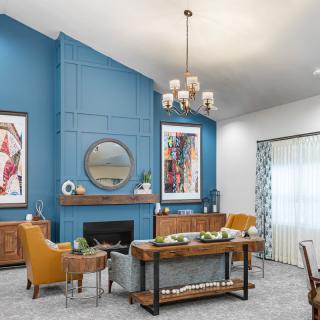 A modern living room featuring a bold blue accent wall, stylish chandelier, and contemporary furniture.