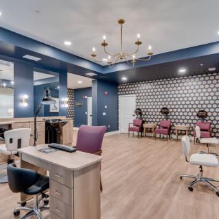 A stylish beauty salon interior with modern decor and a central chandelier.