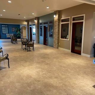 A spacious and well-lit lobby with modern decor, featuring several seating areas with tables and chairs.