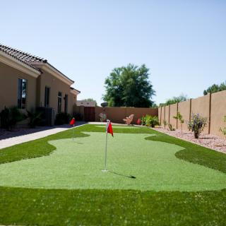 A residential backyard featuring an artificial turf putting green.