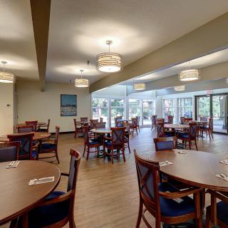 An empty dining area with neatly arranged tables and chairs, well-lit by ceiling lights.