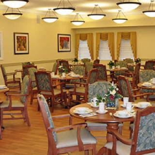 A spacious dining area featuring neatly arranged tables and chairs, adorned with floral centerpieces.