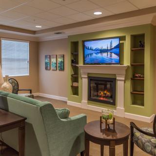 A cozy living room with a fireplace and television, featuring modern decor and comfortable seating.