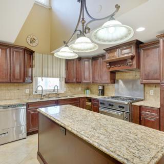 A modern kitchen with wooden cabinets, granite countertops, and stainless steel appliances.