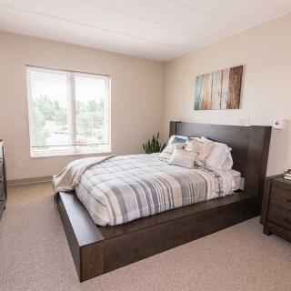 A modern bedroom with a large bed, side tables, and a window letting in natural light.