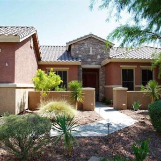A charming single-story house with a stone facade and desert landscaping.