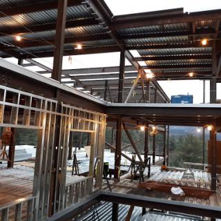 A modern building under construction, showcasing a steel frame structure and interior lighting.