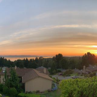 A picturesque sunset over residential rooftops and lush greenery.