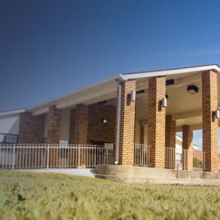 A modern single-story building with brick exterior and steps leading to the entrance, set against a clear blue sky.
