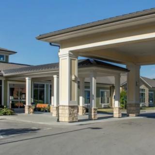 A building with a covered entrance and driveway on a sunny day.