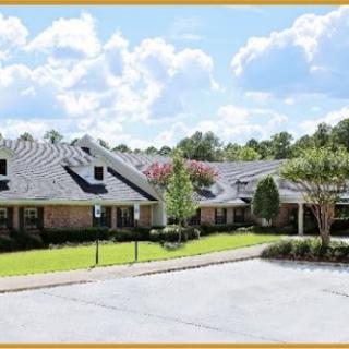A charming residential building surrounded by lush greenery and a clear blue sky.