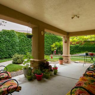 A cozy patio with potted plants and outdoor seating, surrounded by lush garden greenery.