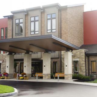 A modern building entrance with a stone facade and covered entryway.