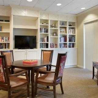 A cozy living room with bookshelves, a table, chairs, and a television.