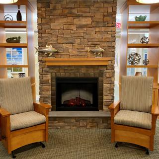 A cozy living room setting with two chairs in front of a brick fireplace and built-in shelves.
