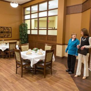 Two people conversing in a well-lit dining area with set tables.