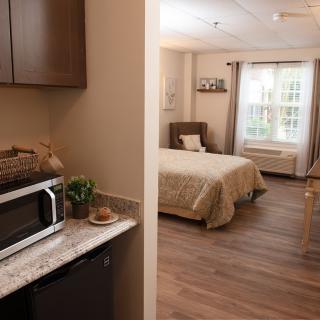 A cozy, modern bedroom with natural light and a kitchenette.
