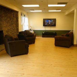 A cozy living room with sofas, a fireplace, and a television on the wall.