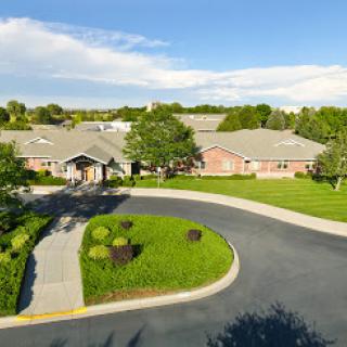 Aerial view of a residential building surrounded by lush greenery and a winding road.
