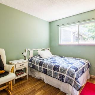 A cozy bedroom with a single bed, green walls, and a wooden floor.