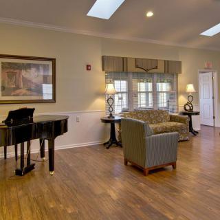 A cozy living room with a grand piano, comfortable seating, and elegant decor.
