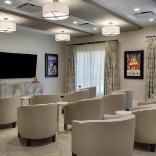 A modern conference room with comfortable chairs and a large television screen, decorated with framed artwork on the walls.
