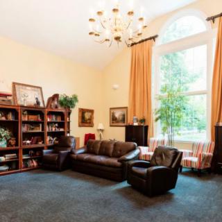 A cozy living room with a large window, elegant chandelier, and comfortable seating.