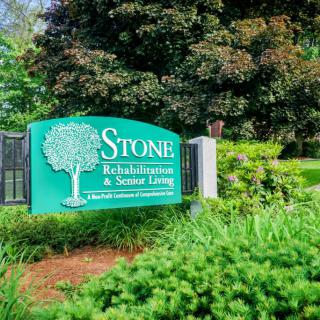 Entrance sign for Stone Rehabilitation and Senior Living surrounded by greenery.