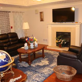 A cozy living room with leather sofas, a coffee table, and a fireplace beneath a wall-mounted TV.